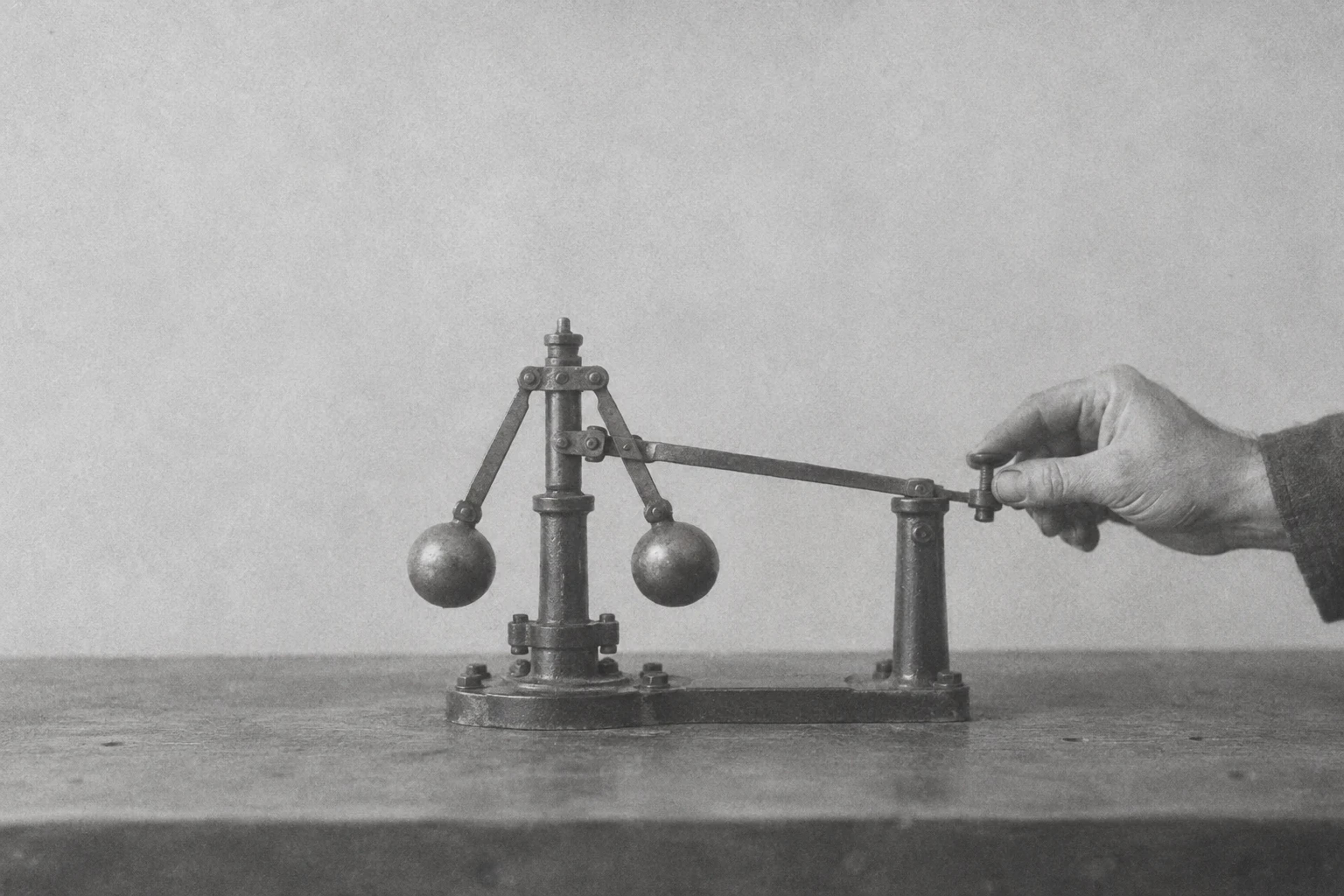 Grainy monochrome illustration of a hand adjusting a mechanical feedback governor.
