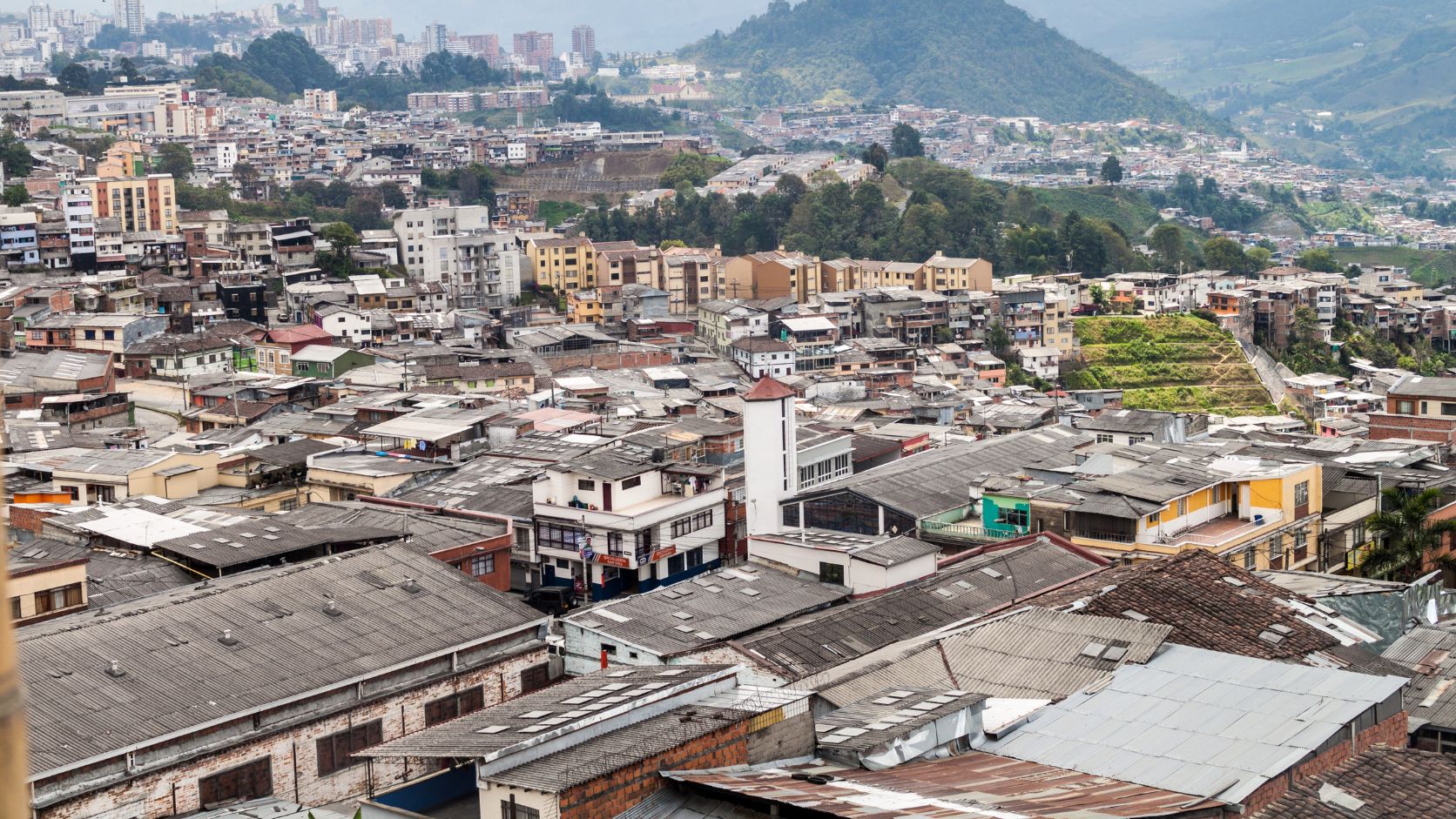 Manizales: tejados y viviendas cubriendo la ladera, con la ciudad y la montaña al fondo.