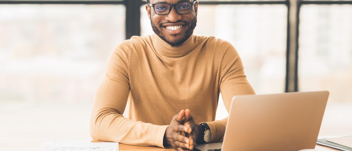 A smiling IT Director at a desk representing a non-profit organisation supported by Newcorp's Microsoft 365 Backup and Recovery service.