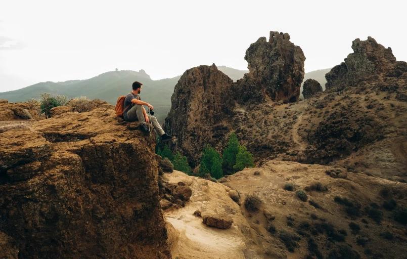 Person sitting high on a rock looking out to the other rocks.