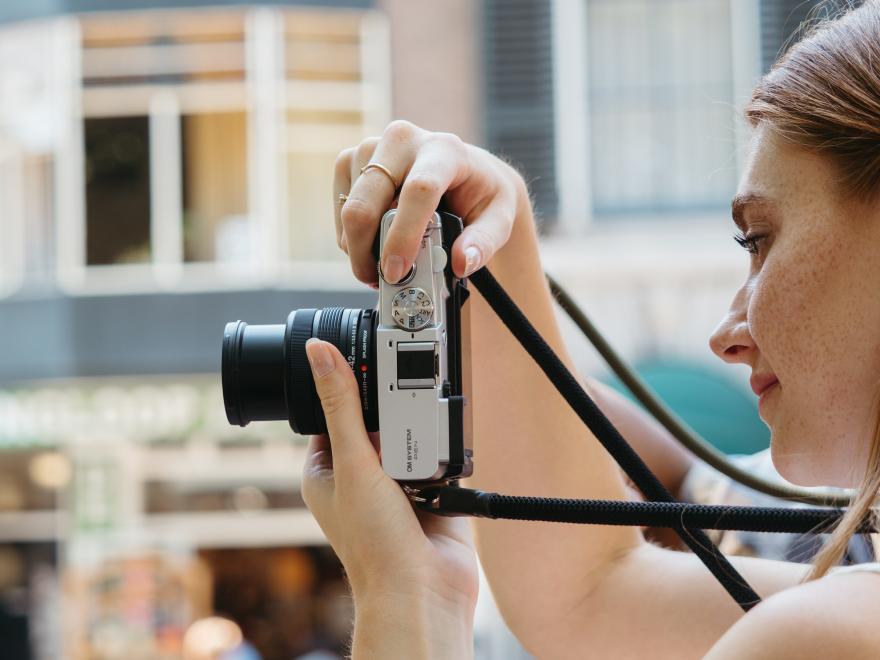 Camera is a girls hands with her taking a photo.