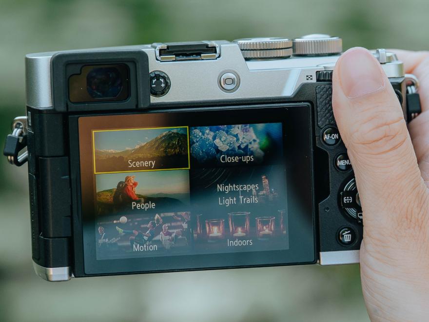 Camera in hand with scene modes screen being viewed on the camera LCD