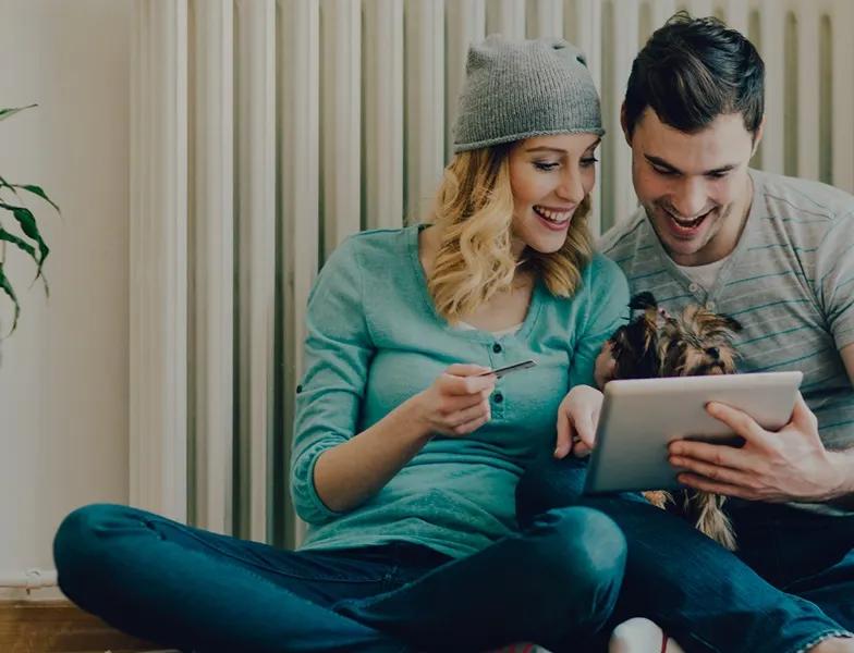 Girl and a boy sitting close to each other and looking at a tablet.