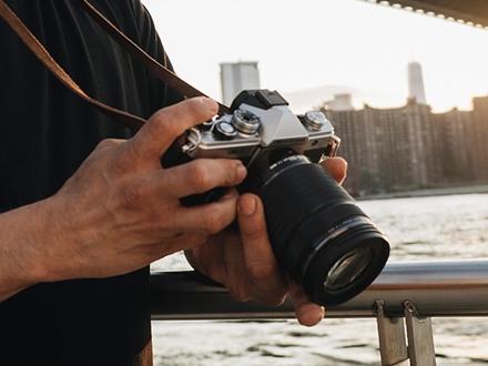OM SYSTEM OM-3 camera in hand rested on a person leg taking a photo.