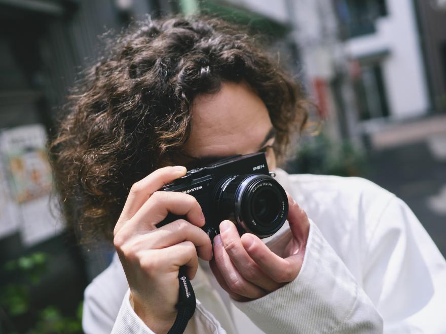 Person with the pen is their hand up to their face taking a photo.