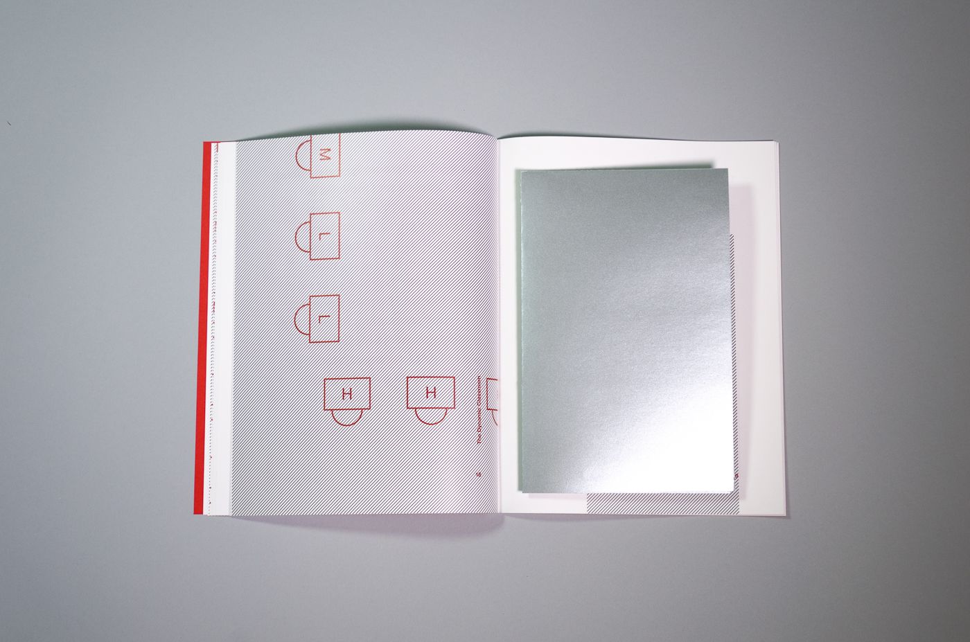 A folded poster printed on silver paper sits in the center of the book.
