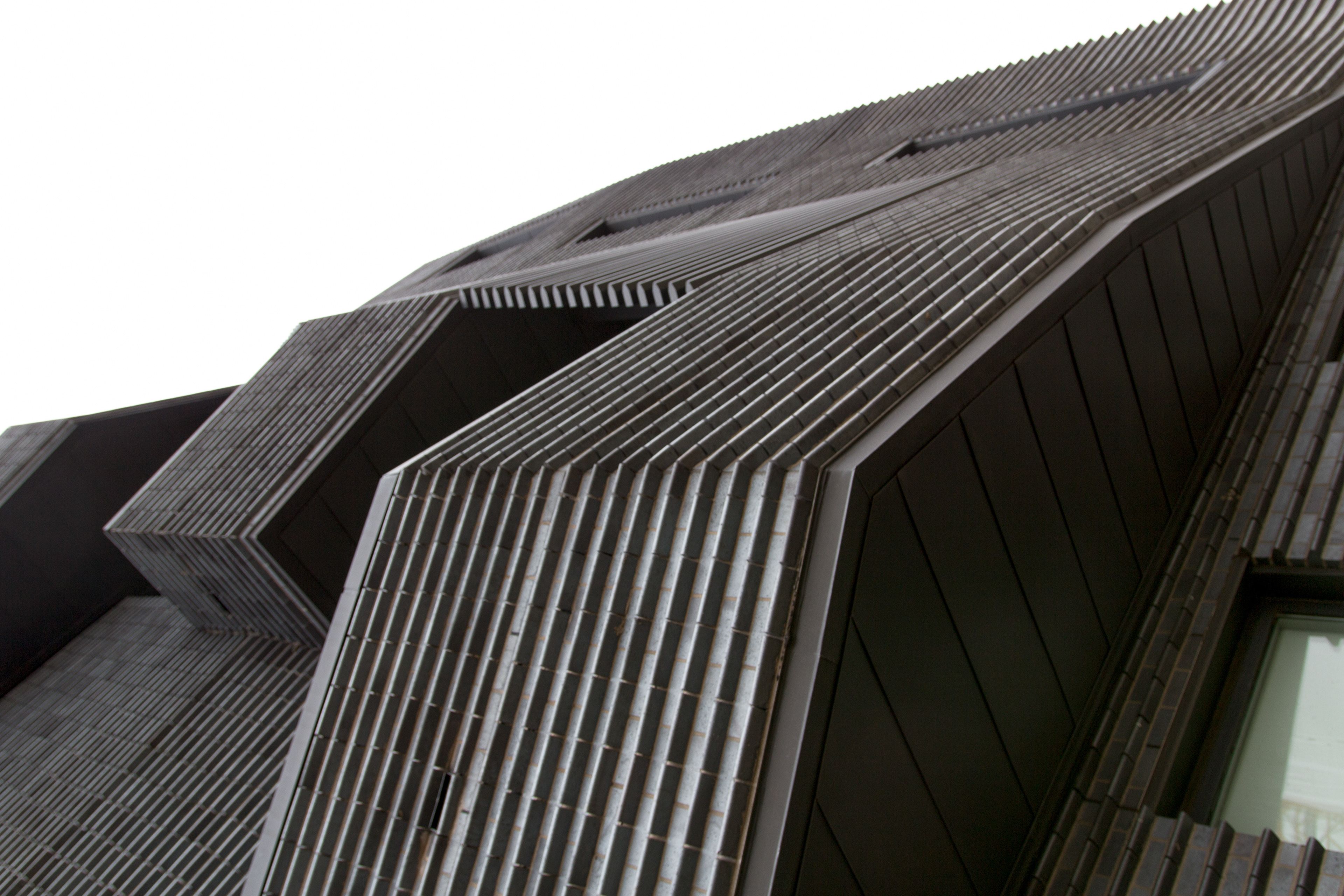A modern black brick building, photographed at an angle that makes it unclear which way is up.