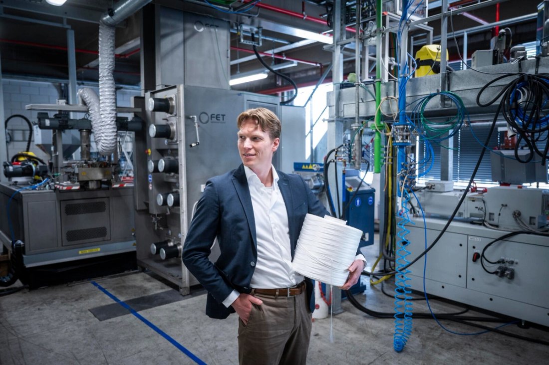 Senbis managing director Gerard Nijhoving standing in an industrial space holding a spool of biopolyester.