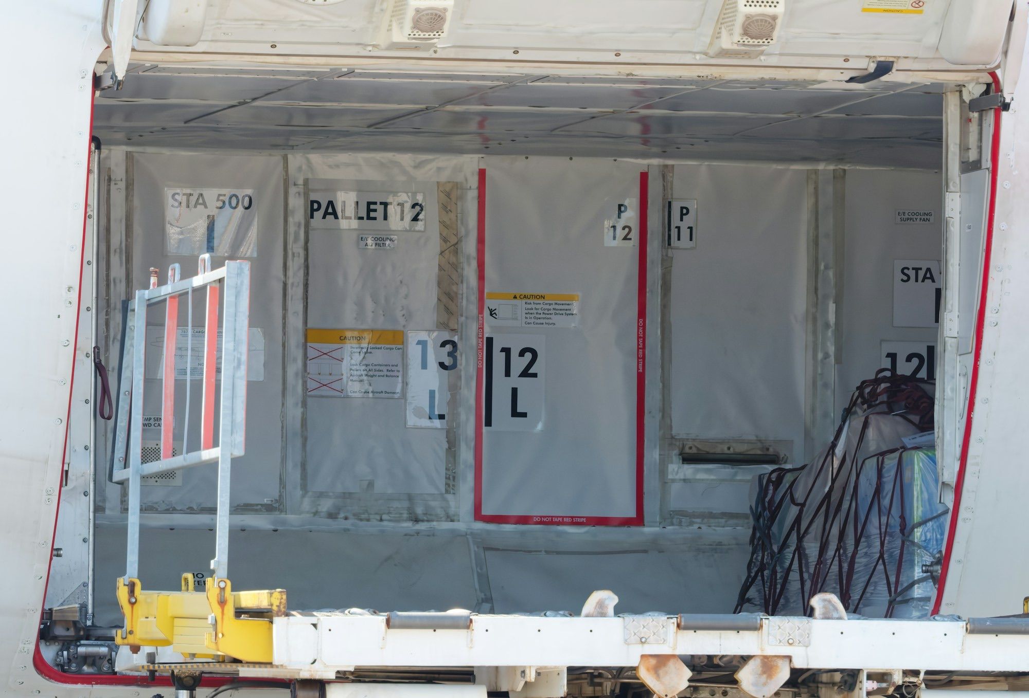 Open cargo hold of a freighter aircraft with netted air freight pallets