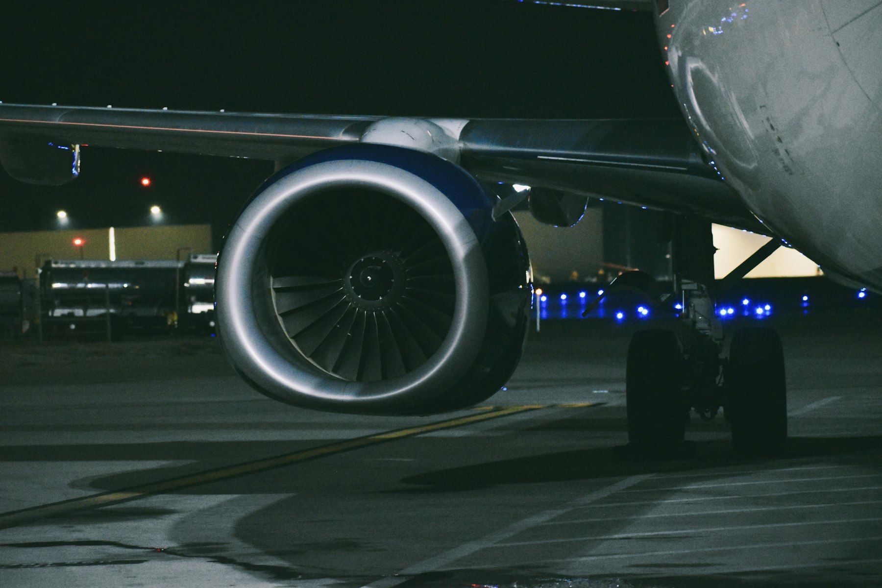 Airliner engine nacelle and landing gear on a night ramp under taxiway lights