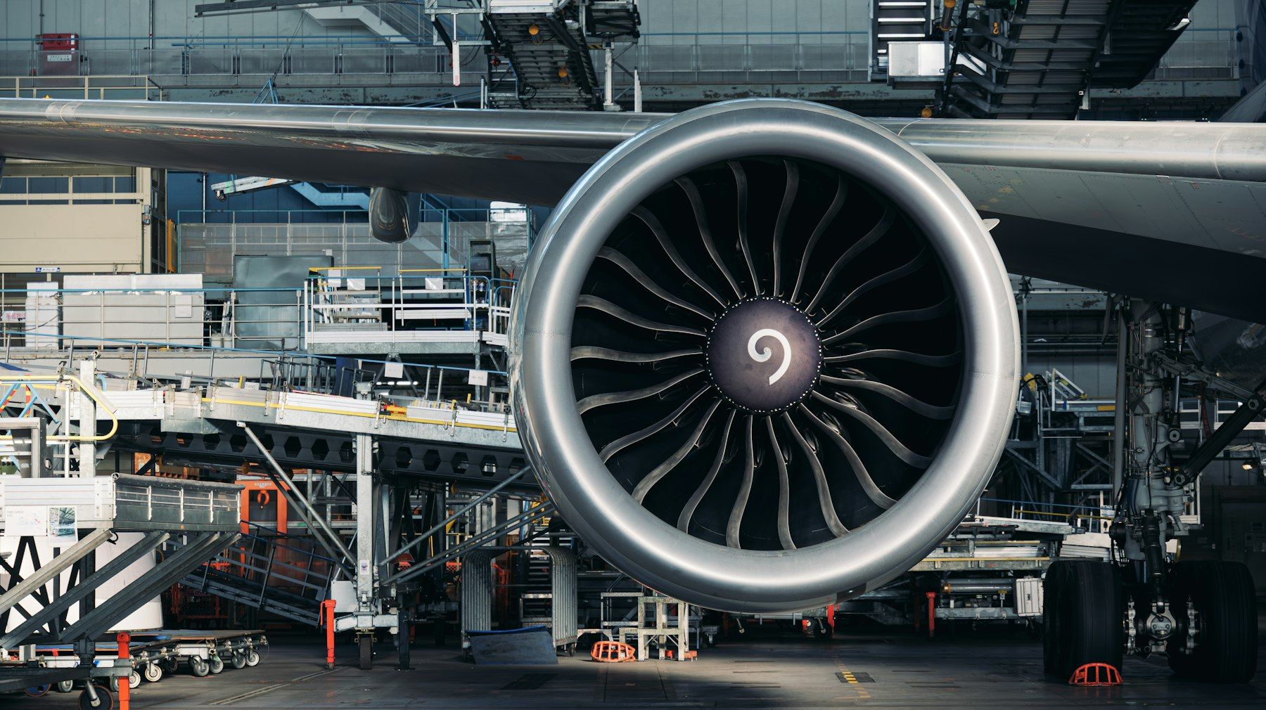Widebody turbofan engine under a wing inside a maintenance hangar