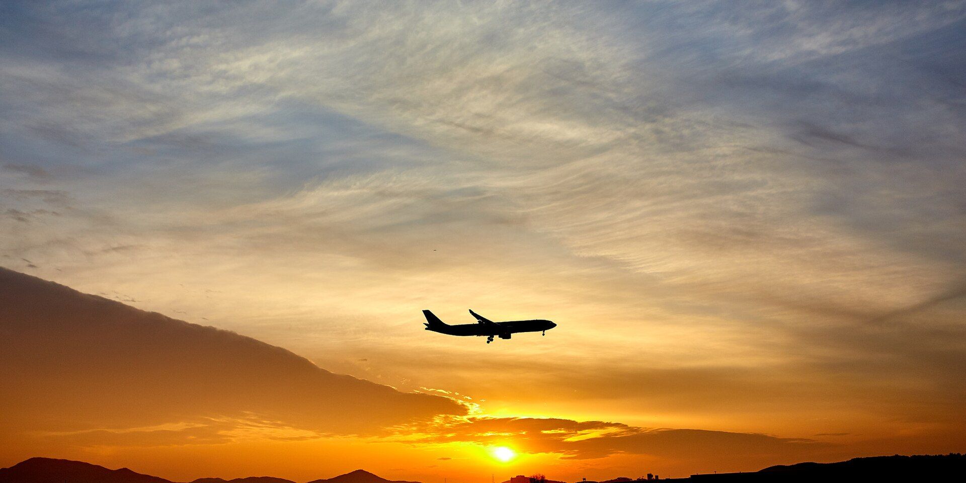Airliner silhouette on approach against a bright sky