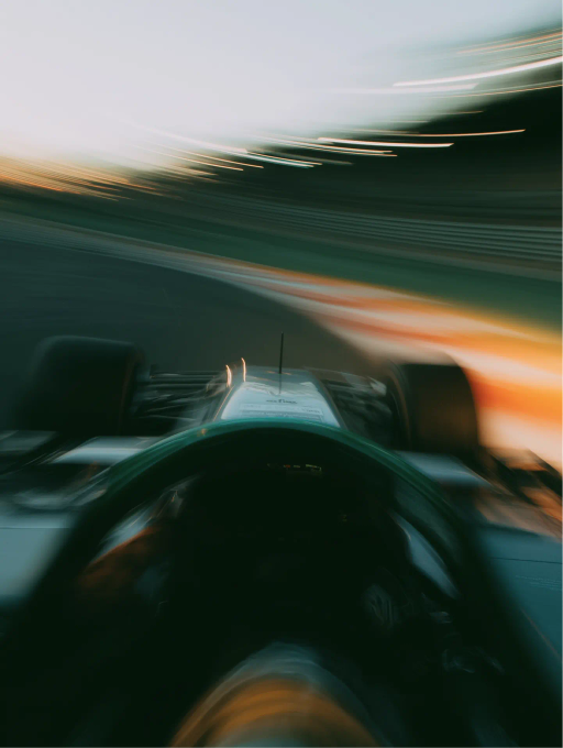 Vista desde el volante de un coche de carreras en una curva rápida con luces difuminadas que sugieren alta velocidad.
