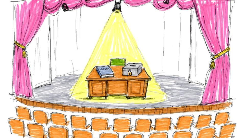 An empty theater stage with pink curtains and rows of orange seats facing a desk holding a ledger and a locked cash box under a spotlight.