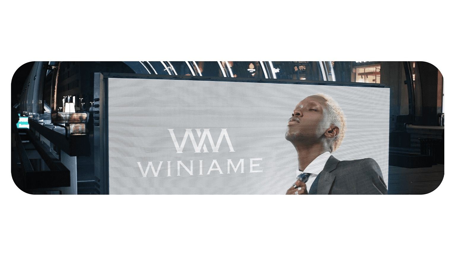 Winiame logo on a large screen beside a model in a suit