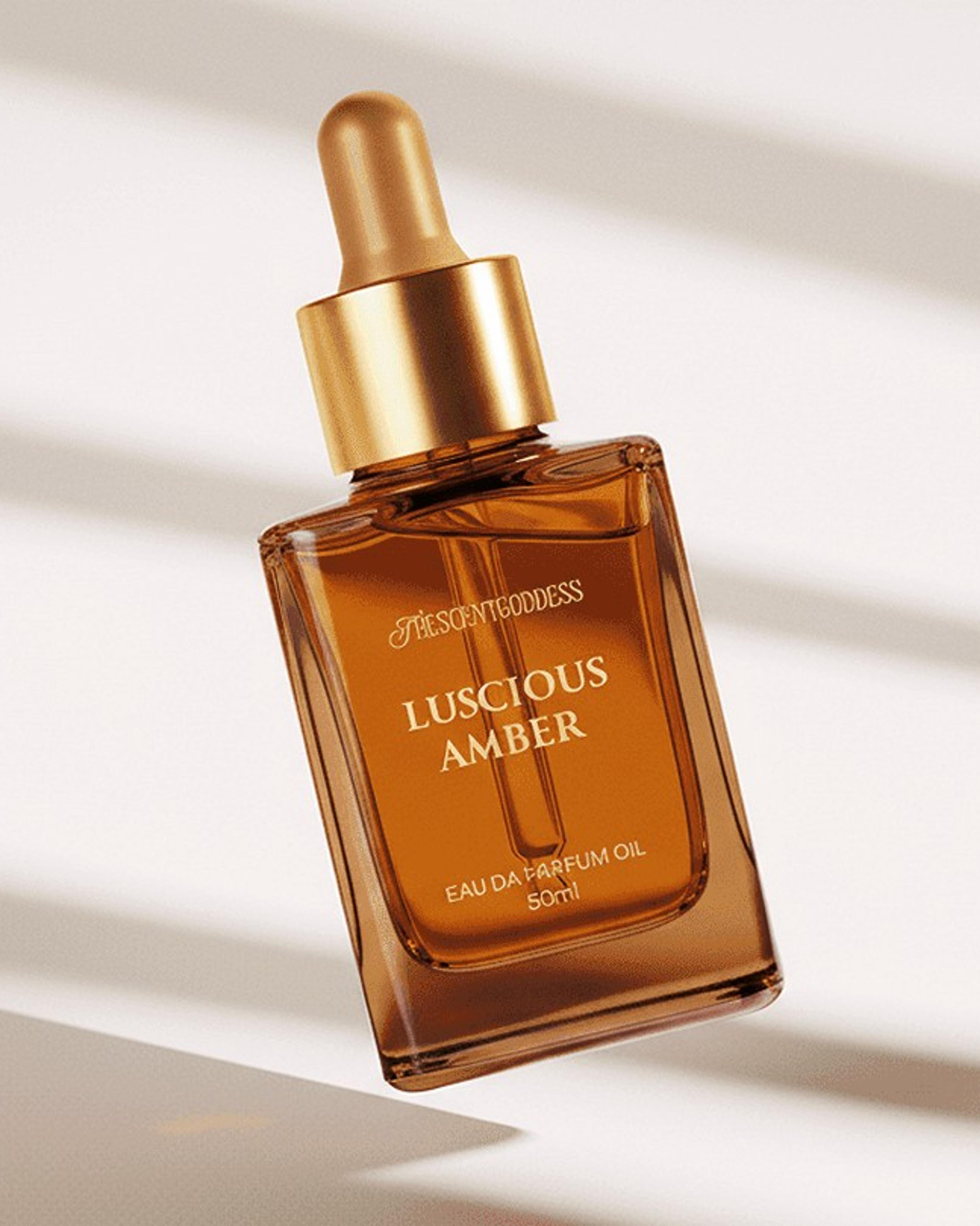 An amber Luscious Amber perfume bottle with a gold dropper, floating in soft window light