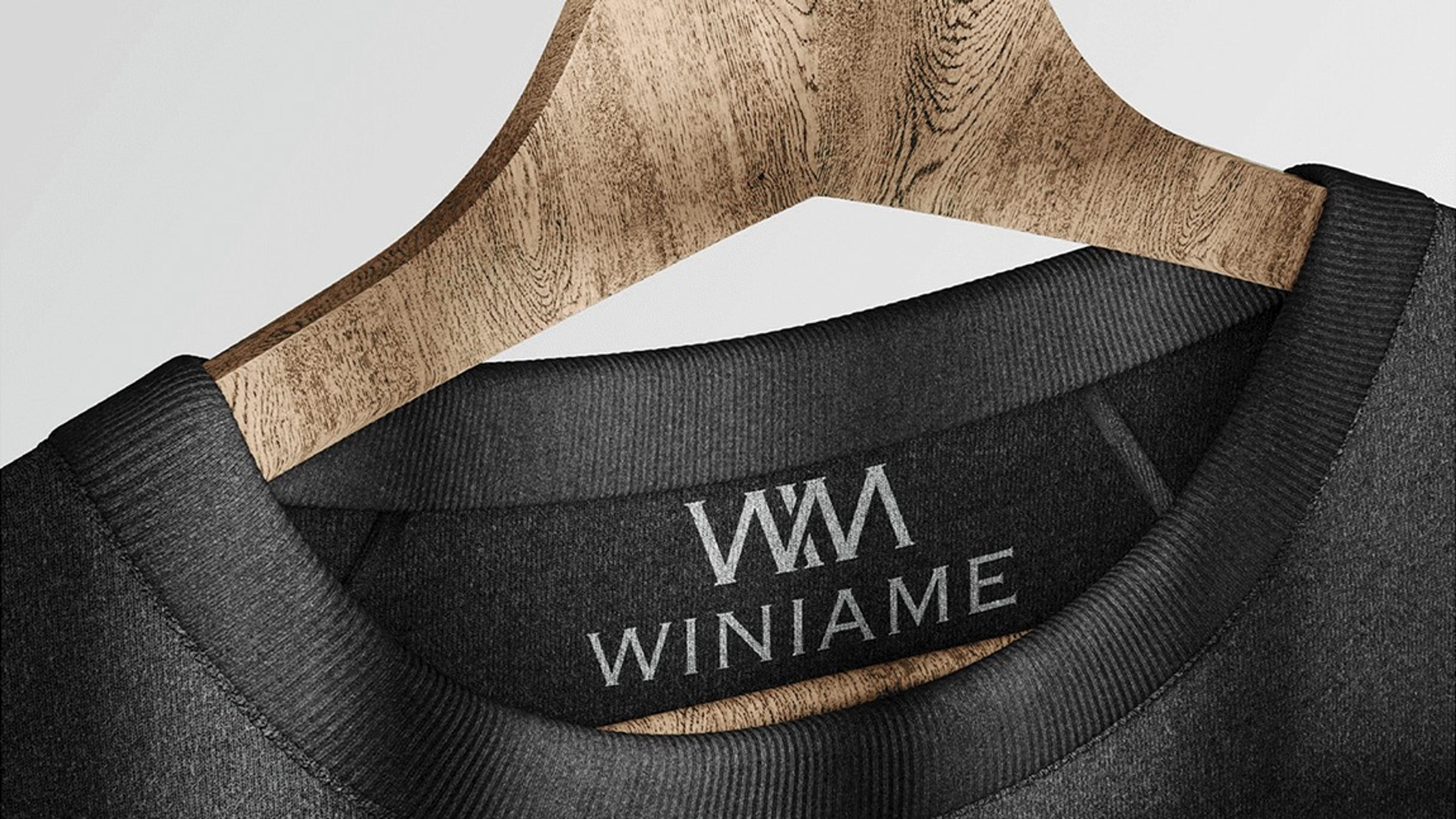 Black sweater on a wooden hanger with the Winiame neck label
