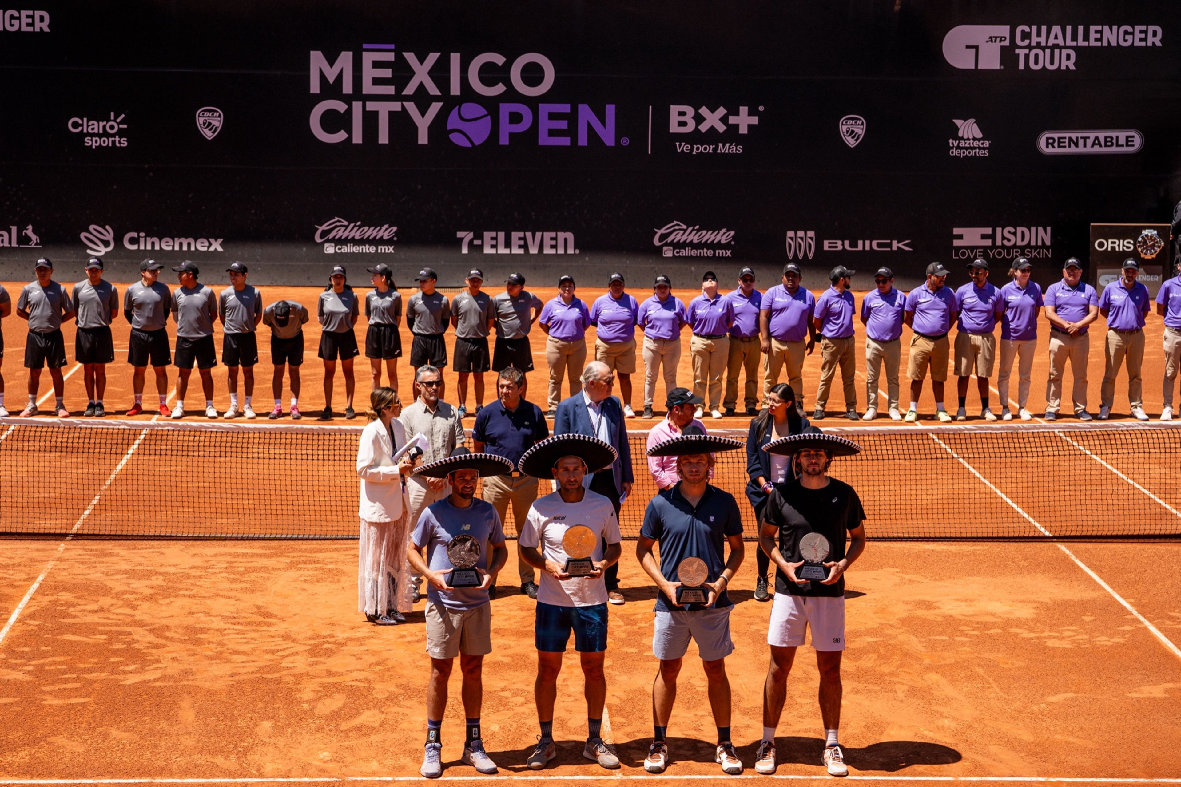 Premiación en la cancha central: cuatro jugadores con sombrero de charro sostienen sus trofeos frente a jueces y recogepelotas.