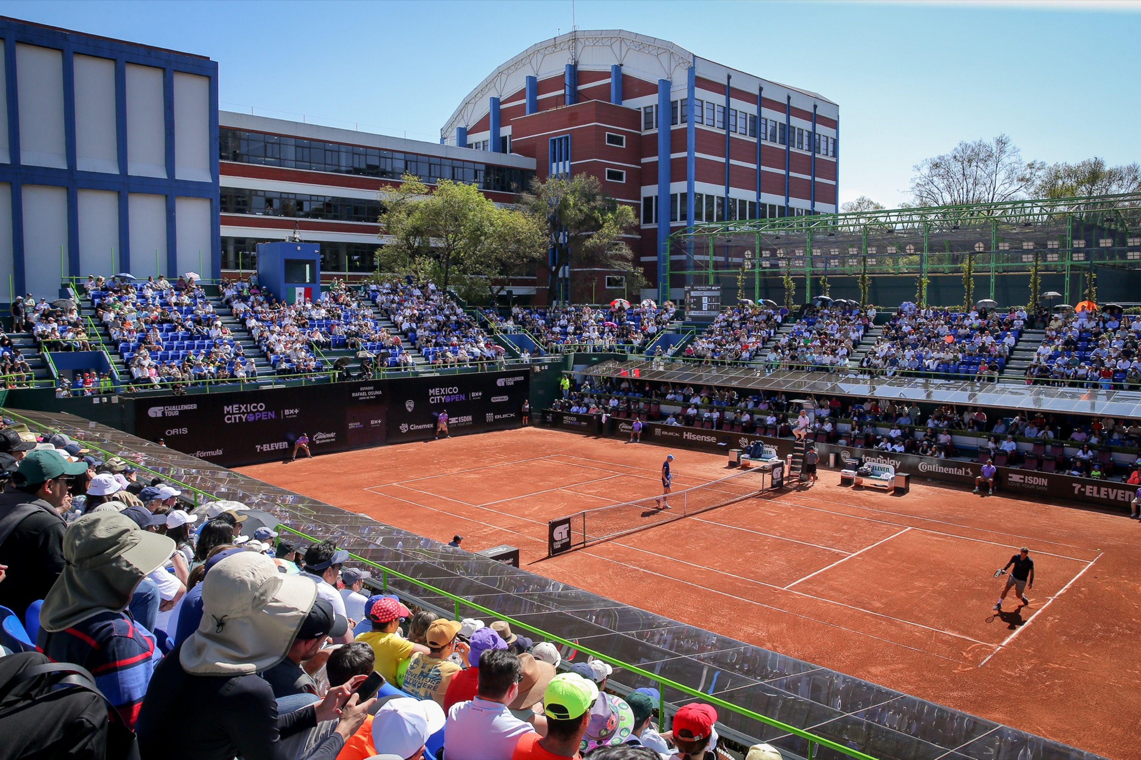 Partido en la cancha central de arcilla del Mexico City Open, con las gradas llenas bajo el sol.