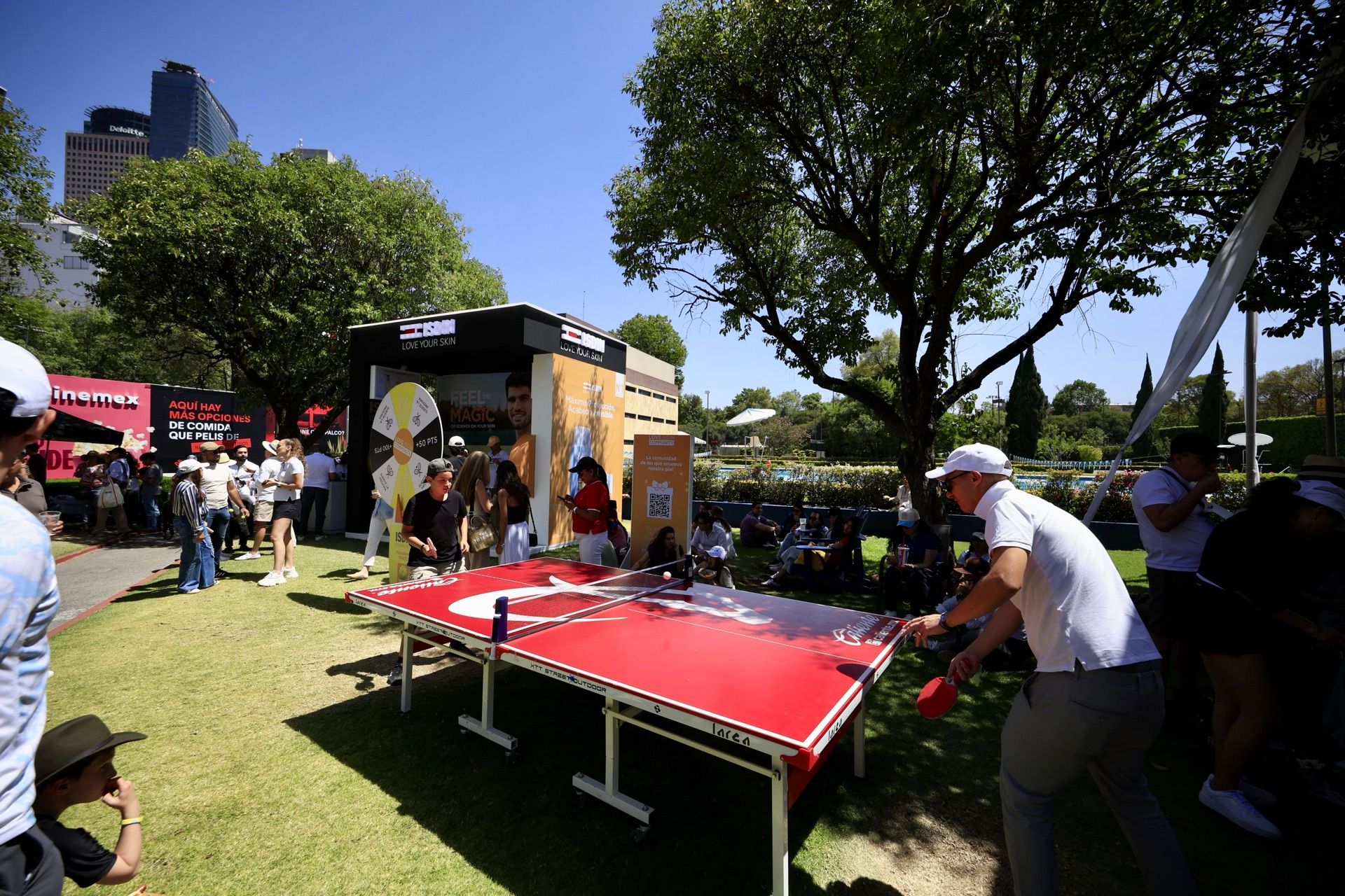 Activación de marca en el jardín del torneo: aficionados juegan ping-pong junto a los stands de los patrocinadores.