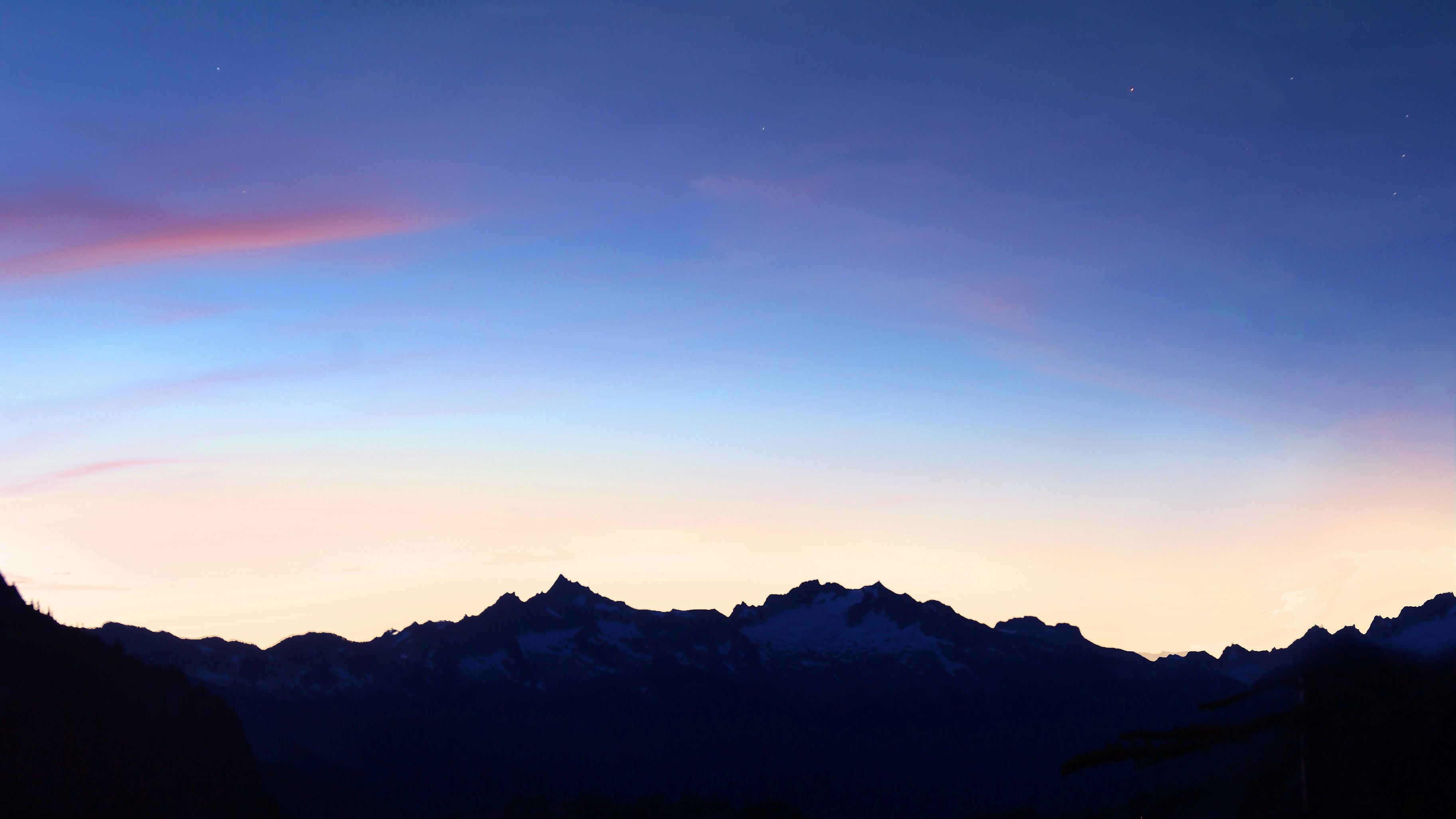 a crescent moon rises over a lake with mountains in the background