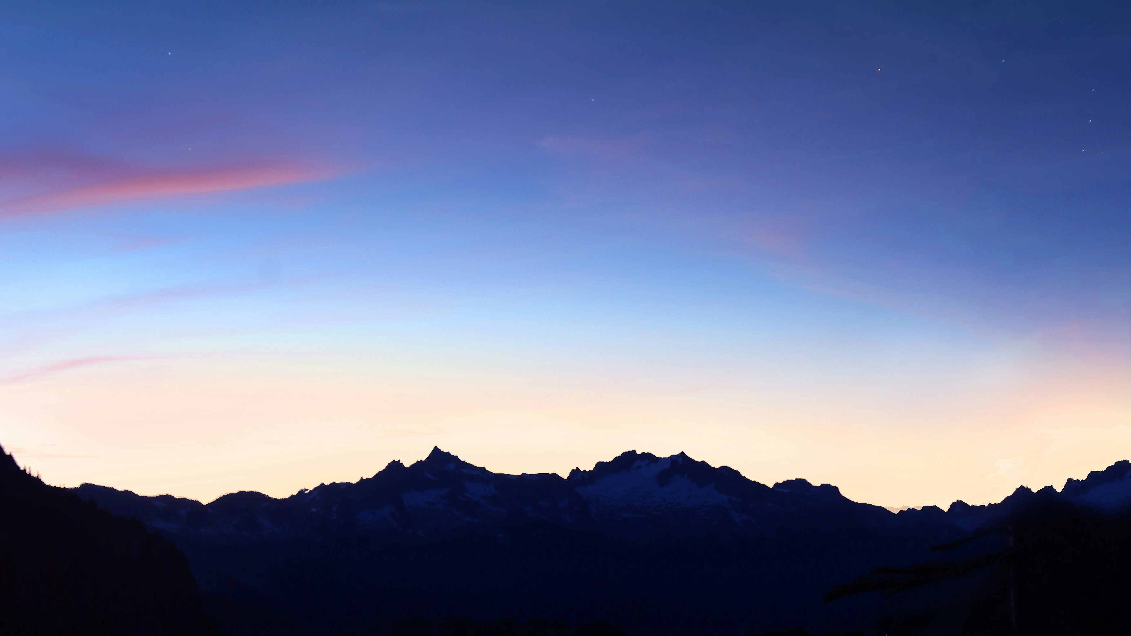 a crescent moon rises over a lake with mountains in the background