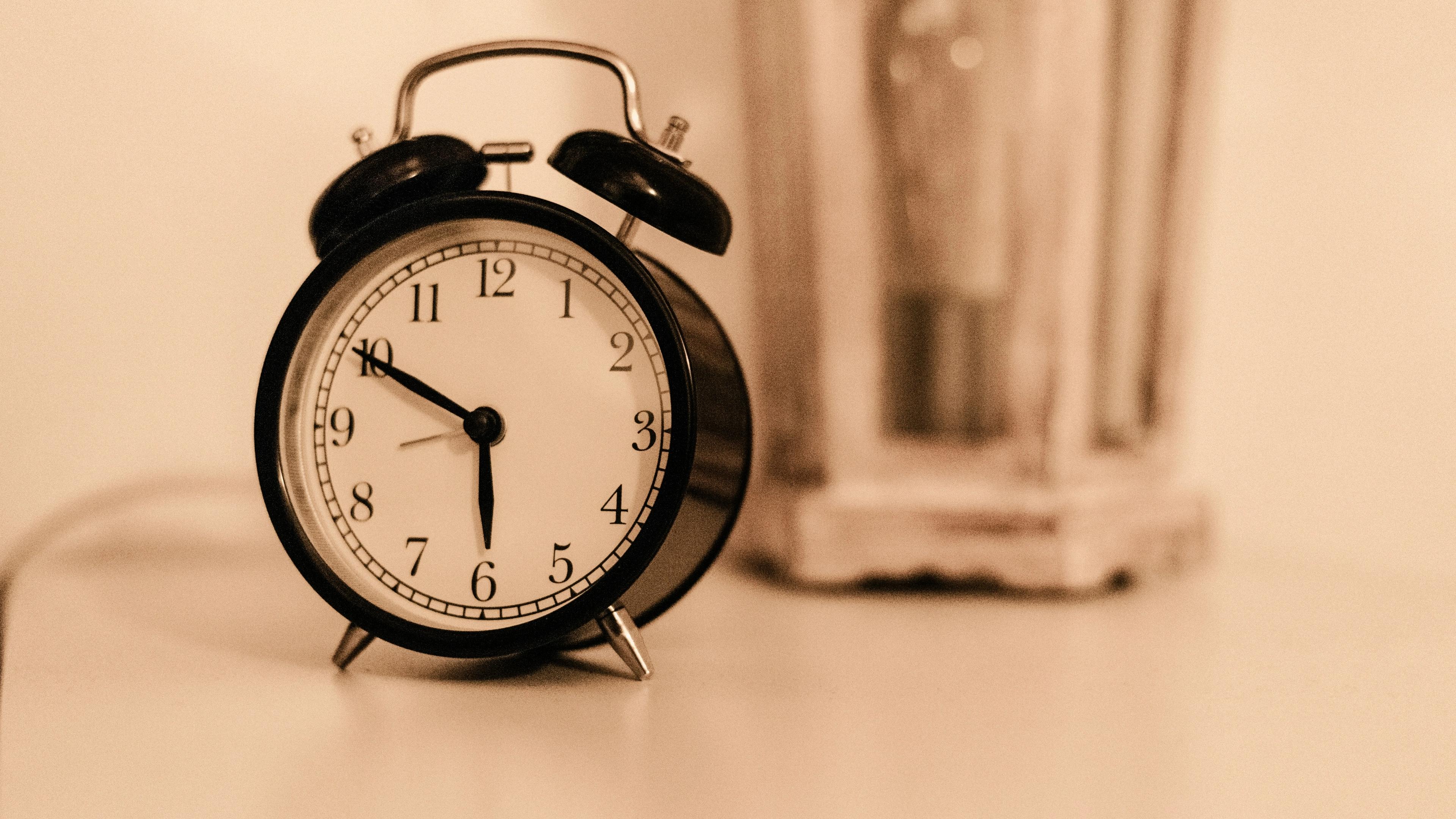 an alarm clock is sitting on a table next to a lamp .