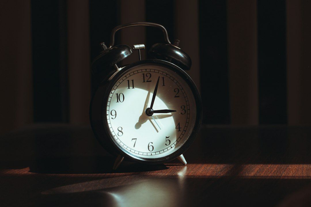 A vintage alarm clock sits on a wooden surface - Photo by Suhas Hanjar on Unsplash