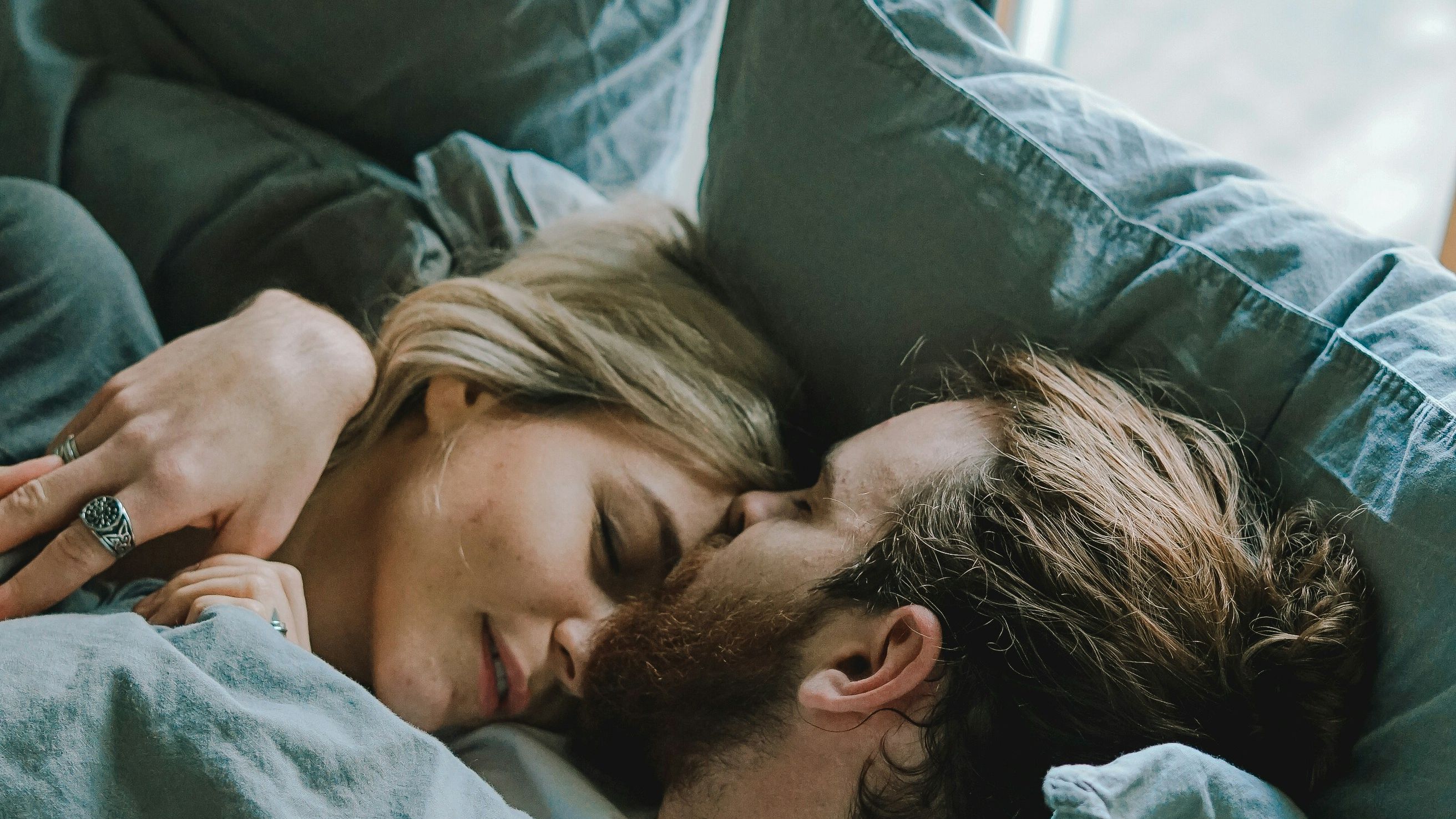 a man and a woman are laying in bed under a blanket