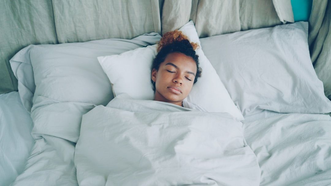 Young African American woman is sleeping in comfortable bed under warm blanket having rest on beautiful linen. Comfort, resting people and bedroom concept. - Photo by Vitaly Gariev on Unsplash