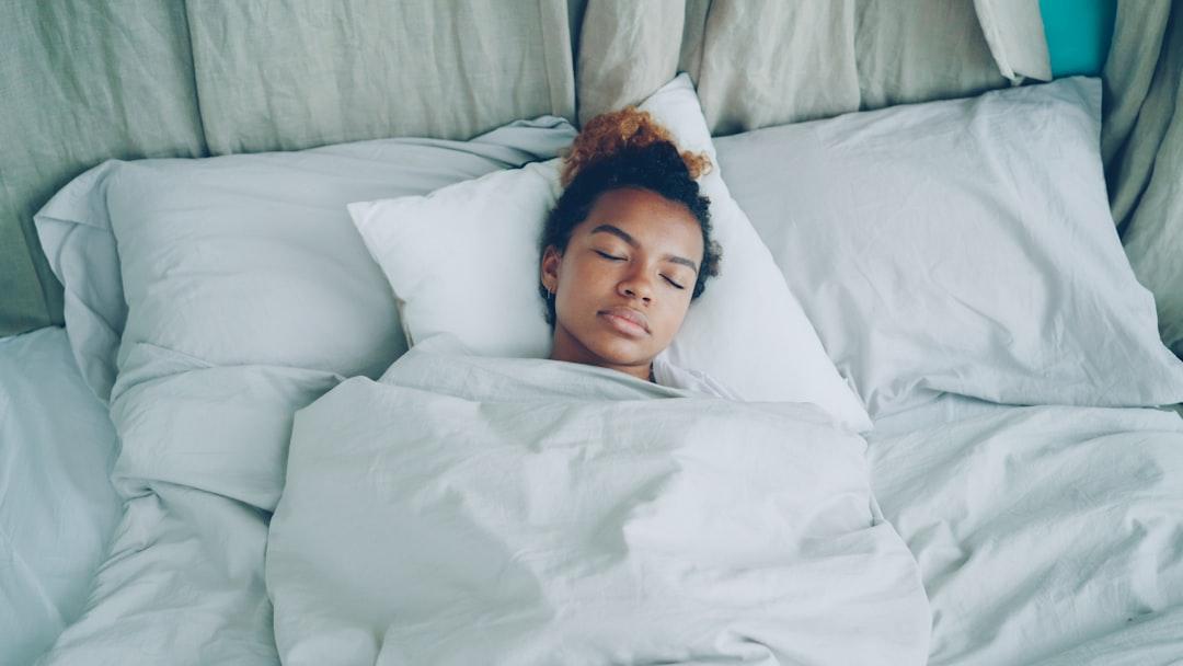 Young African American woman is sleeping in comfortable bed under warm blanket having rest on beautiful linen. Comfort, resting people and bedroom concept. - Photo by Vitaly Gariev on Unsplash