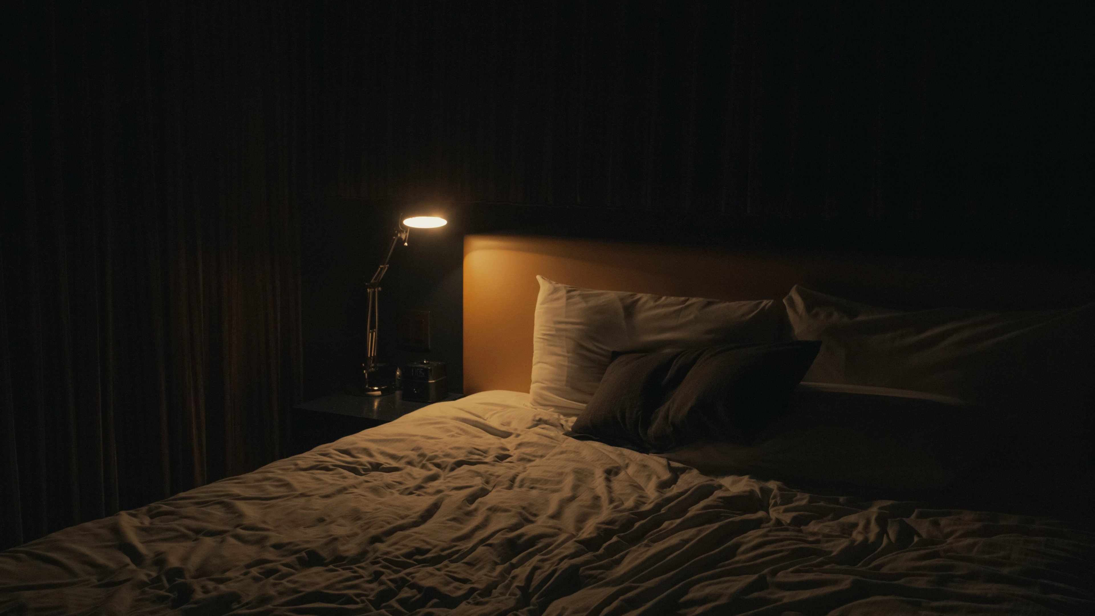 a bed with a lamp on it in a dark room .