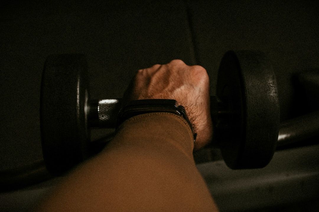 a person's hand holding a barbell in a dark room - Photo by yousef samuil on Unsplash