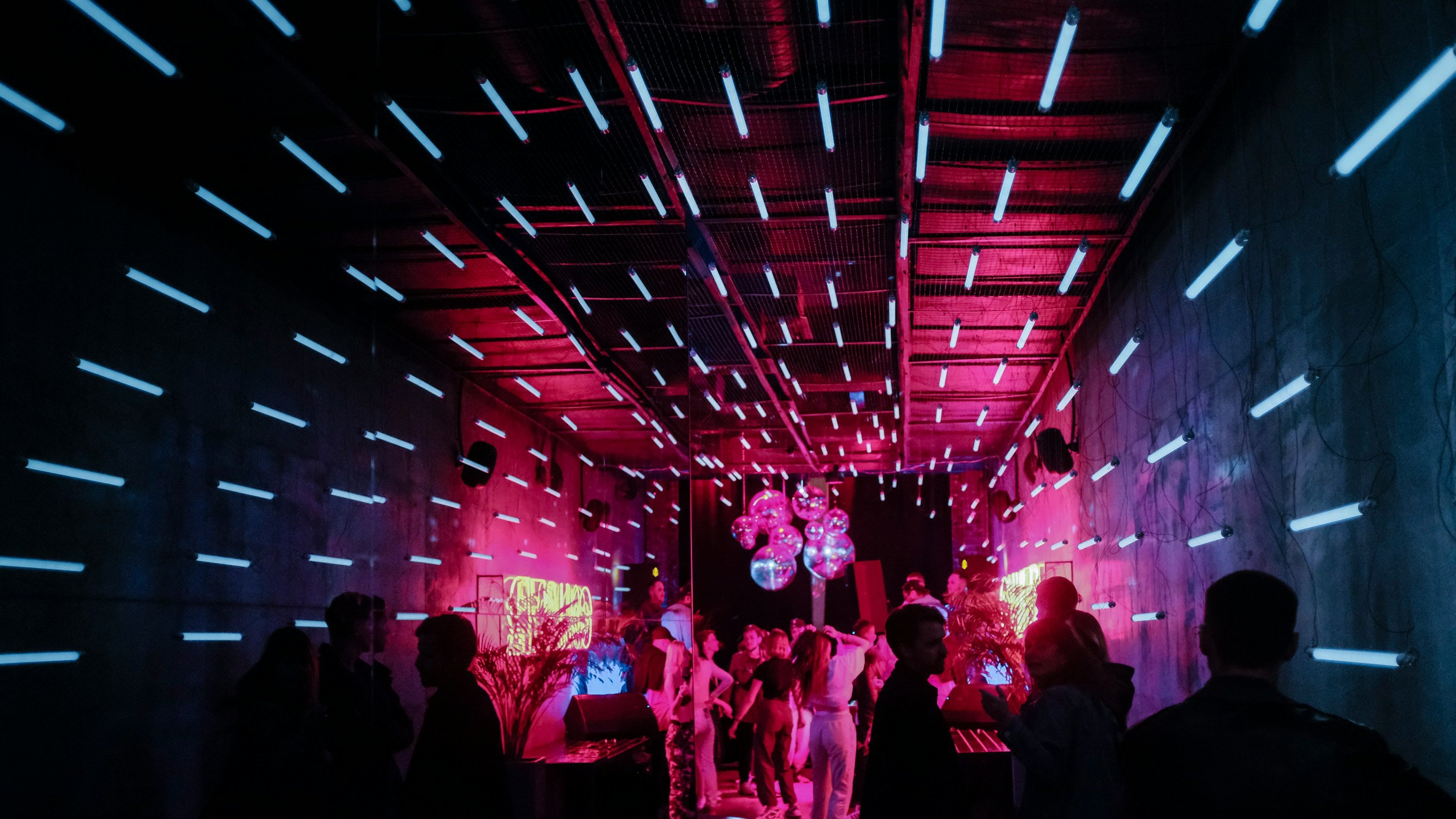 A group of people are dancing in a dark room with neon lights