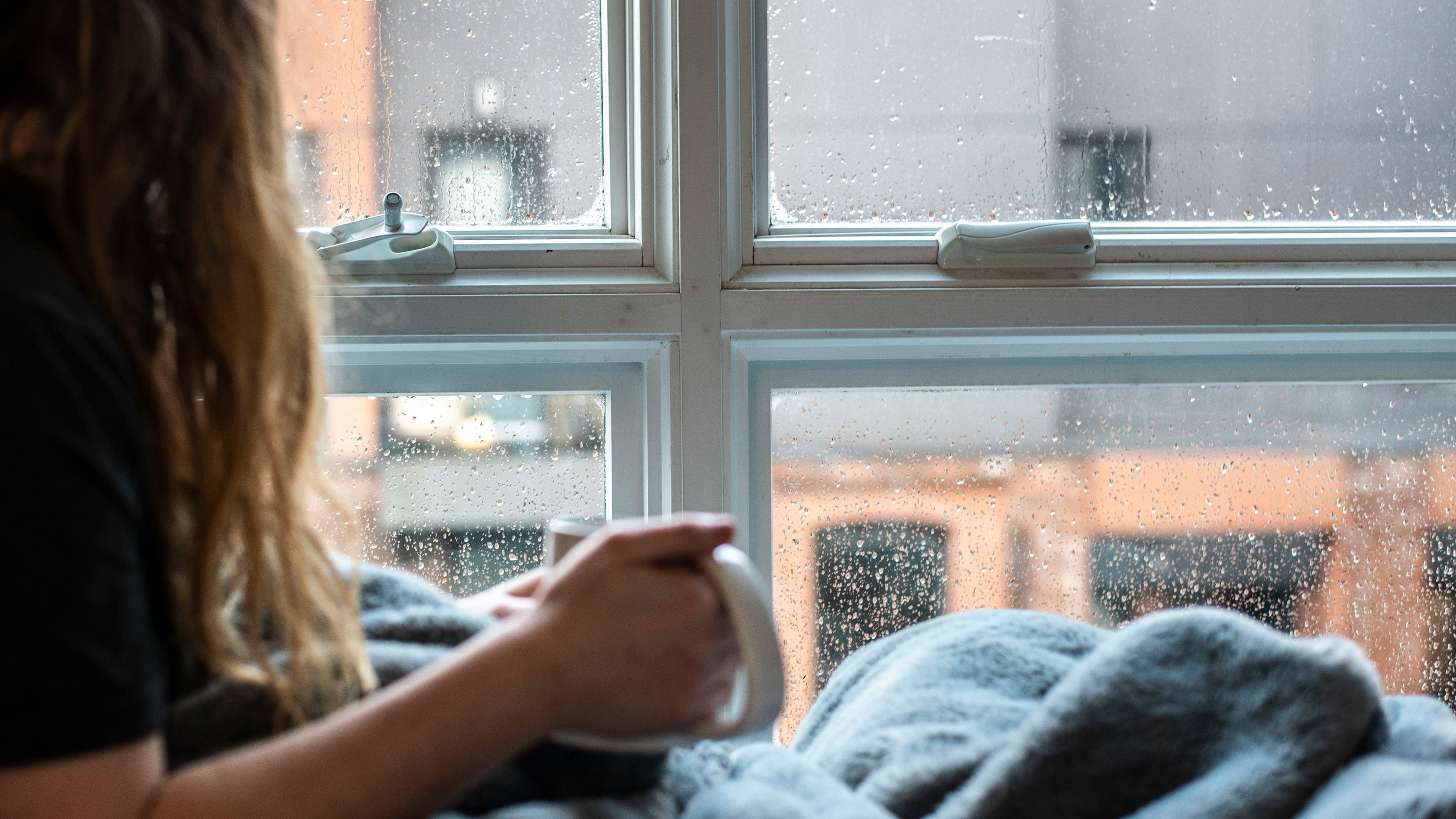 a woman is sitting in front of a window holding a cup of coffee .