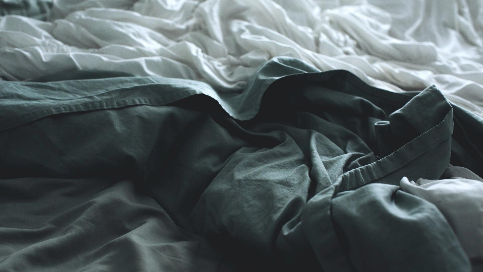 a bed with a lot of blankets and sheets on it .