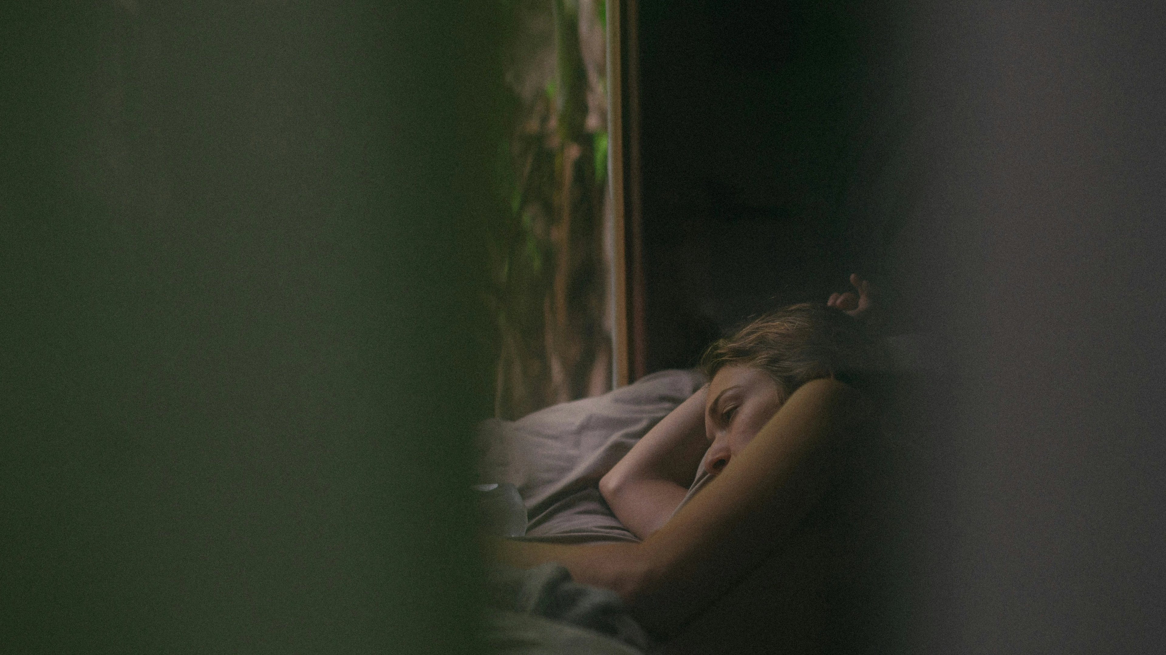 a woman is sleeping on a bed in front of a window