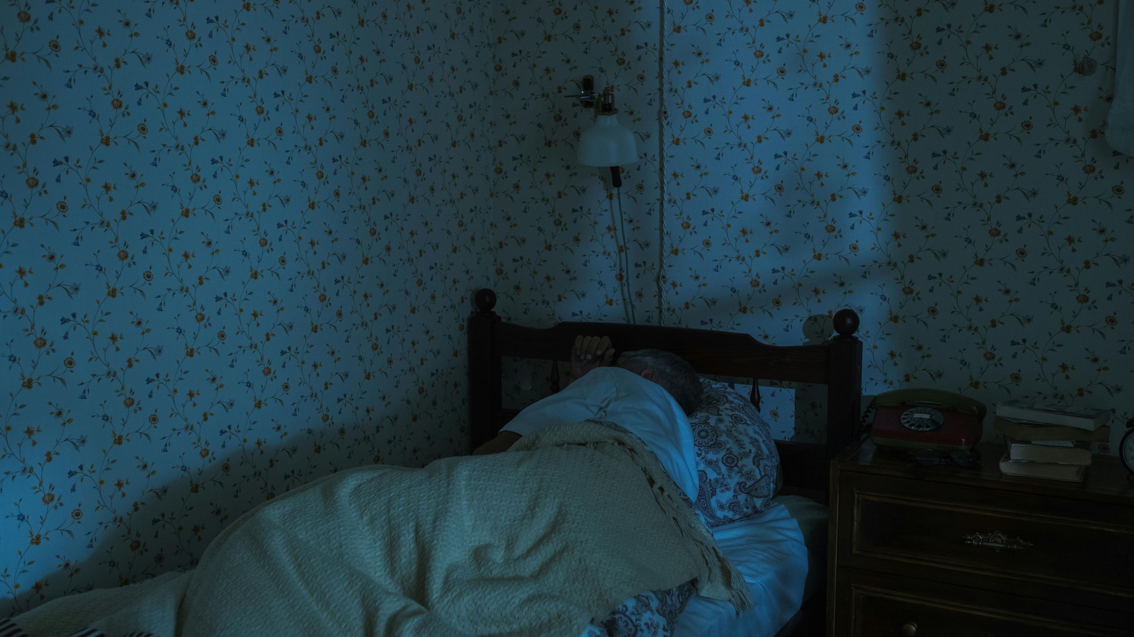 a person is sleeping in a bed in a dark room
