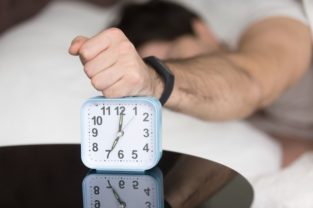 A man laying in bed with a clock on top of him - Photo by Solving Healthcare on Unsplash