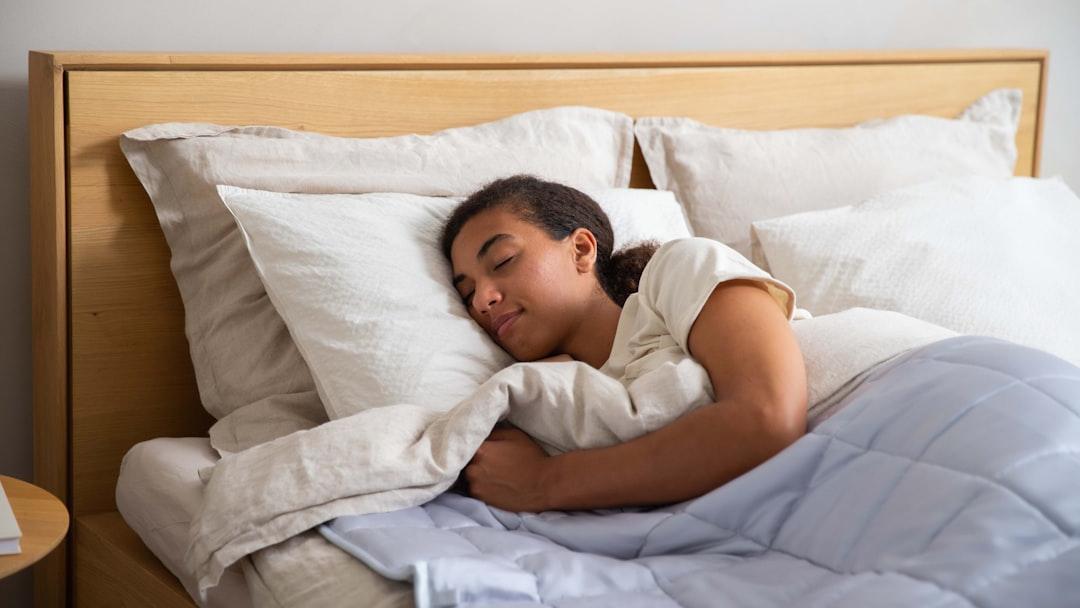 a young girl sleeping in a bed with white sheets - Photo by Slaapwijsheid.nl on Unsplash