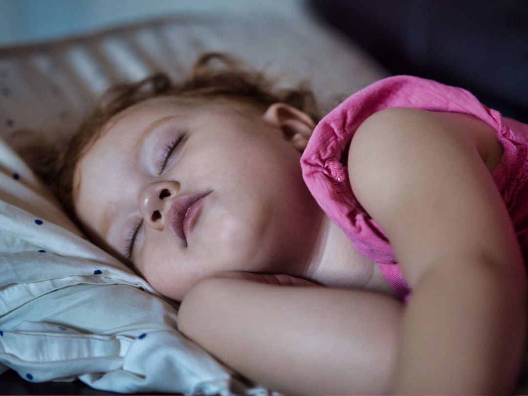 a little girl sleeping on a bed with her eyes closed - Photo by Richard R on Unsplash
