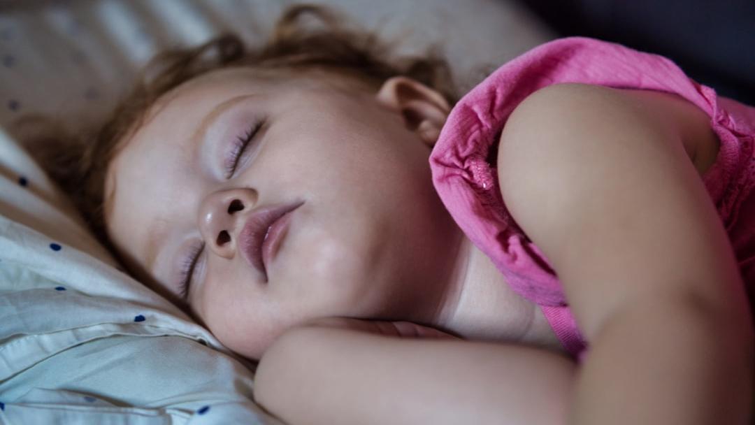 a little girl sleeping on a bed with her eyes closed - Photo by Richard R on Unsplash