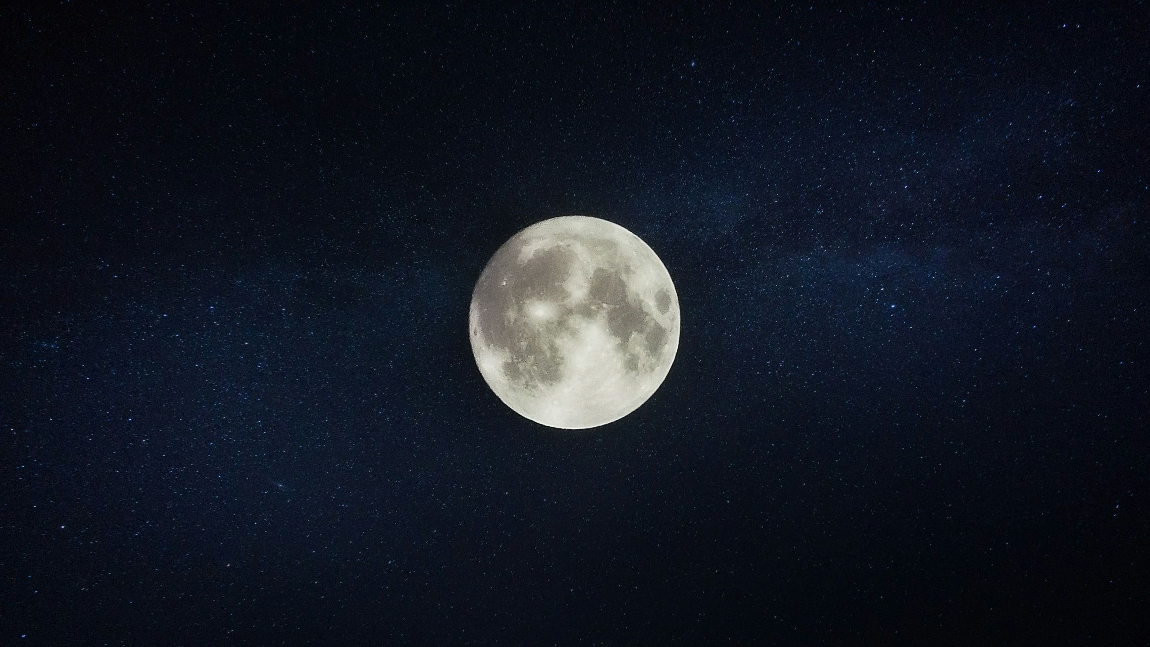 A full moon in a starry night sky