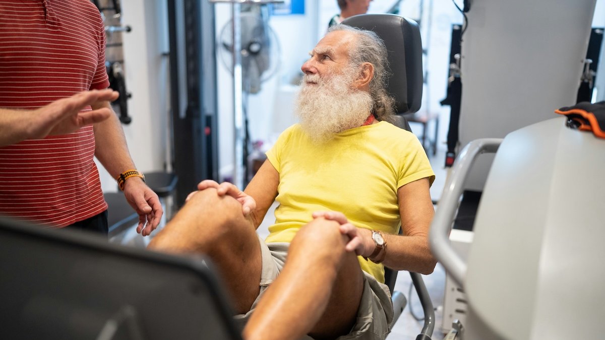 A man with a beard is sitting on a machine in a gym
