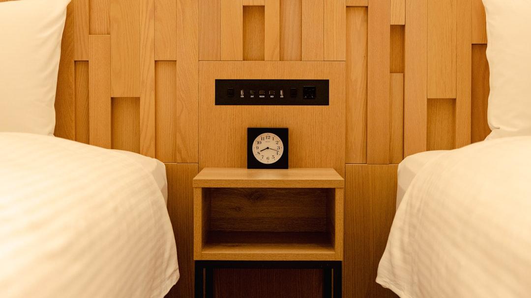 Two beds with a nightstand and clock between them. - Photo by Simon N on Unsplash
