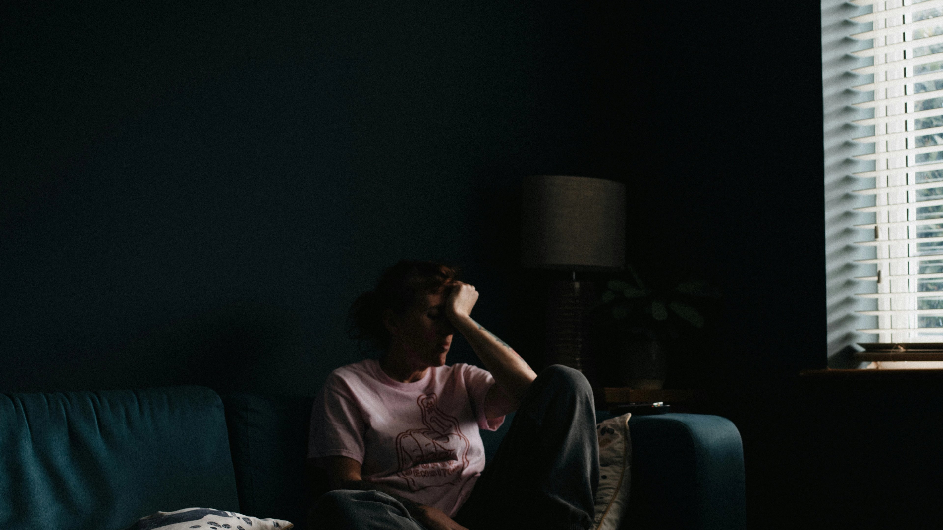 a woman is sitting on a blue couch in a dark room .
