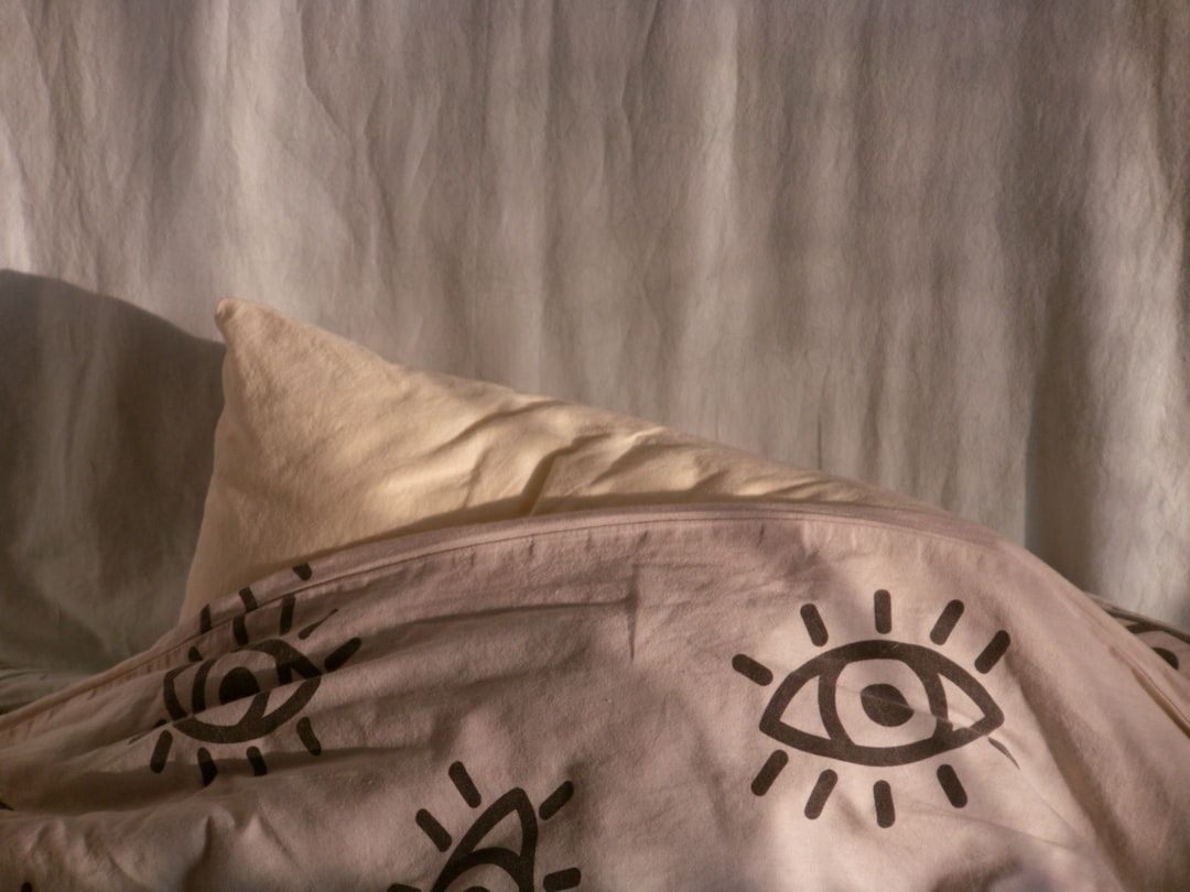 A pillow under a patterned sheet with eye designs - Photo by Efe Kekikciler on Unsplash