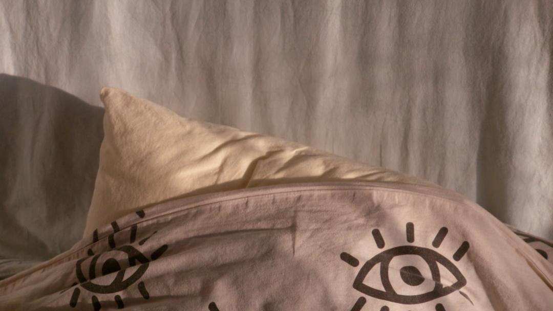 A pillow under a patterned sheet with eye designs - Photo by Efe Kekikciler on Unsplash