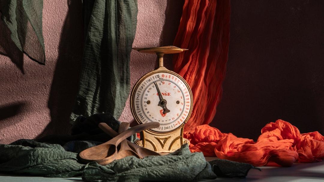 A vintage scale is posed with colorful fabrics. - Photo by Angelo Casto on Unsplash