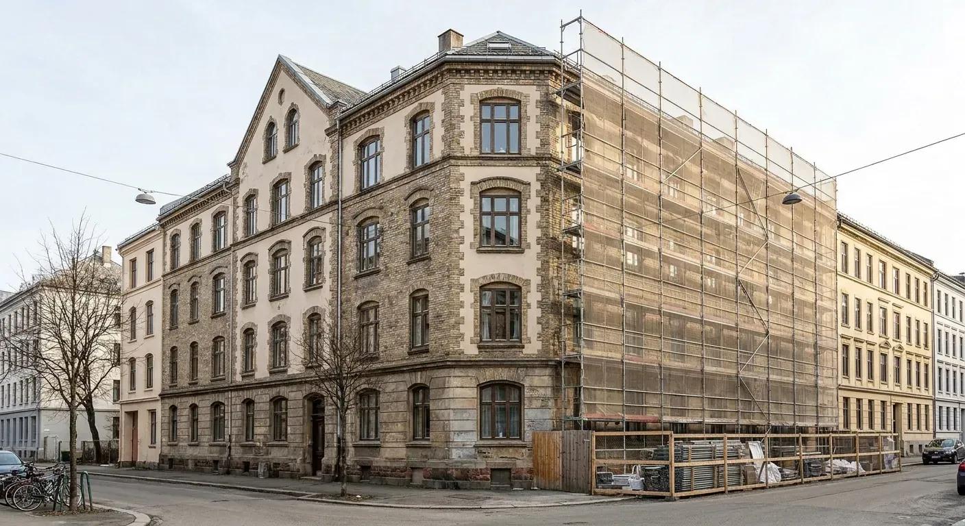A wide shot of a multi-story apartment building in Oslo partially covered in scaffolding with safety netting